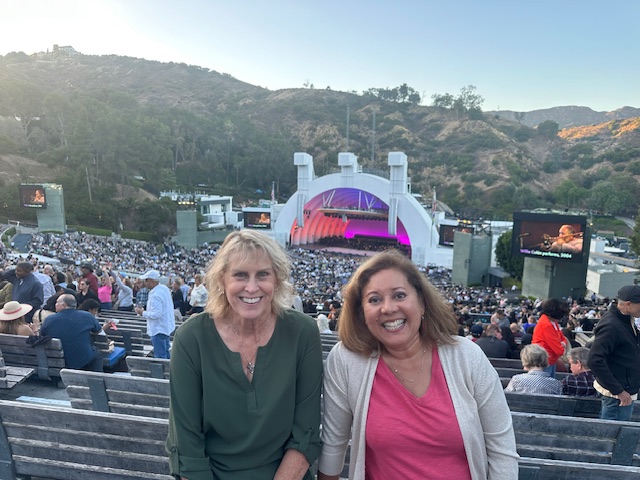 two women seated with the Hollywood Bowl behind them