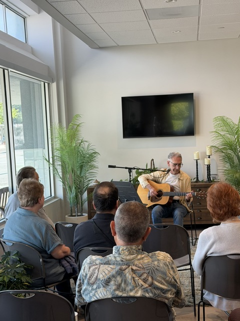 a man playing a guitar to a group of people