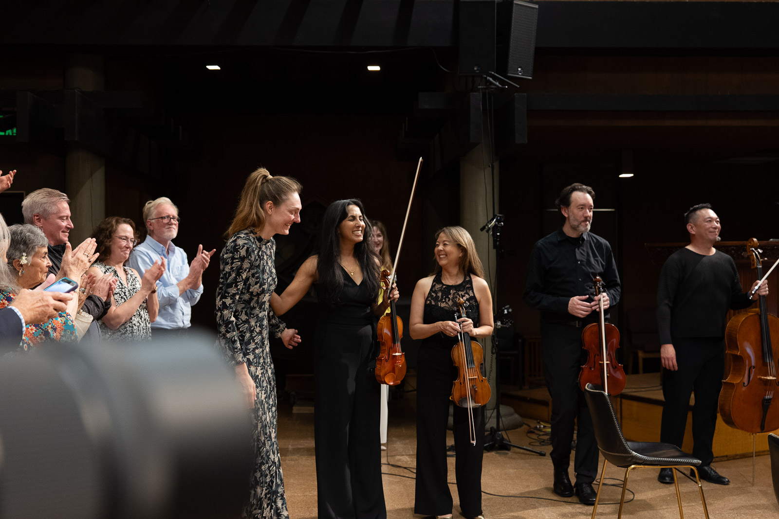 a group of four people standing with their string instruments