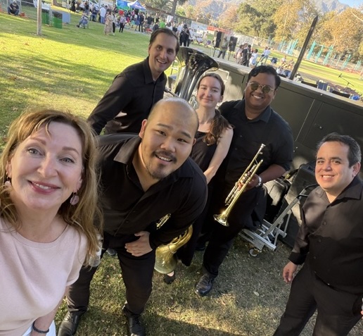 a group holding brass instruments taking a selfie 