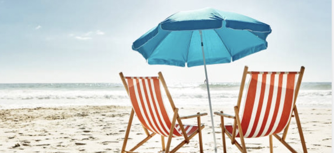 two beach chairs beneath a blue umbrella on the sand